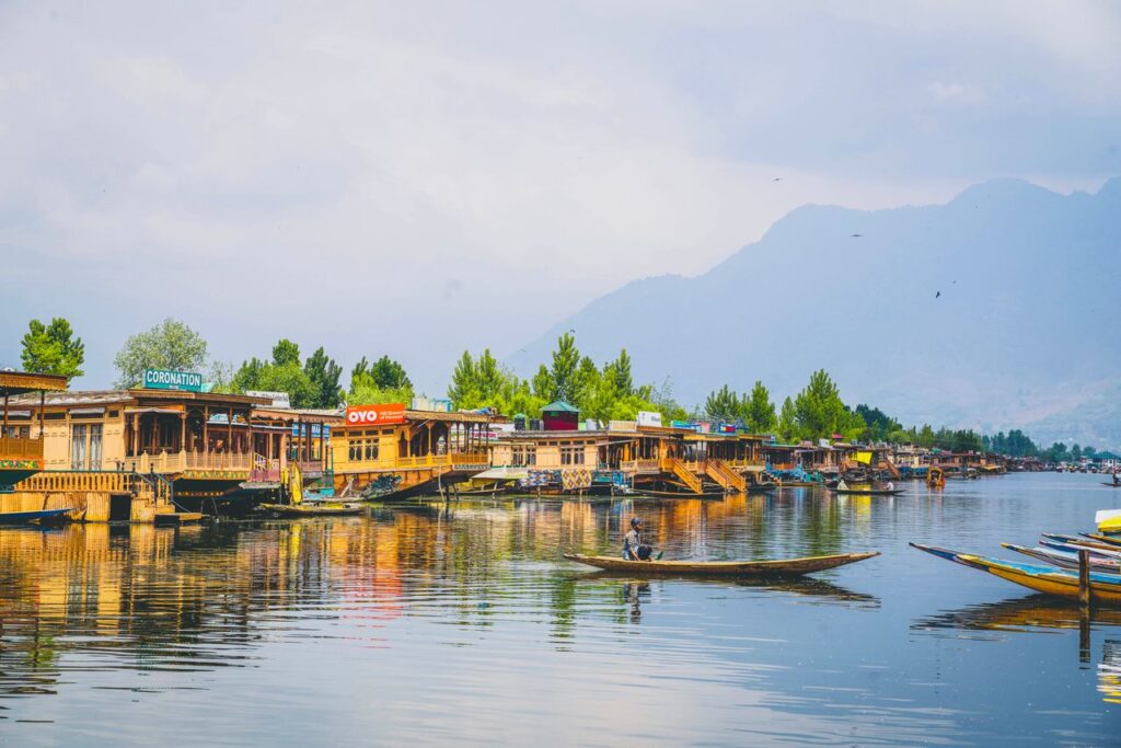 Scenic view of traditional houseboats and shikara on Dal Lake, Srinagar, reflecting serene beauty.