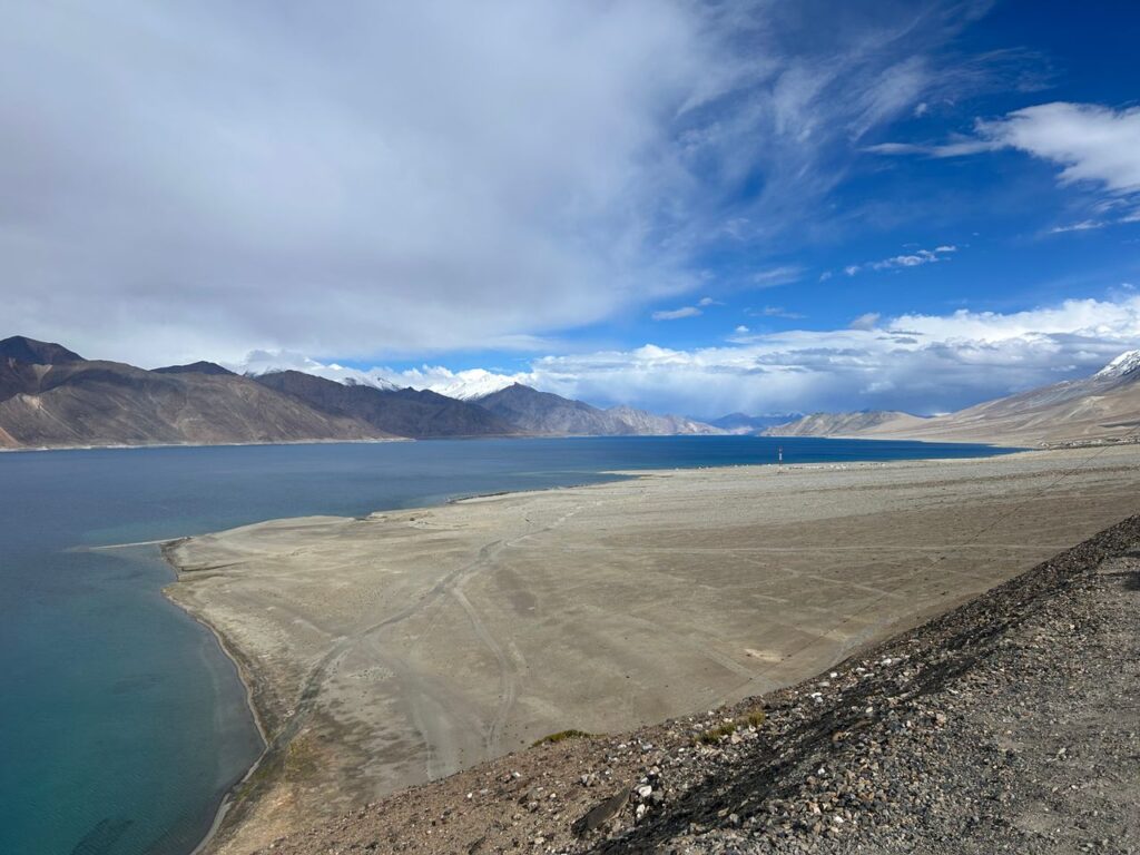 Expansive view of Pangong Lake and surrounding mountains in the Himalayas under a clear blue sky.